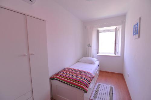 a small white room with a bed and a window at A - luxury apt in center just 5min from beach in Korčula