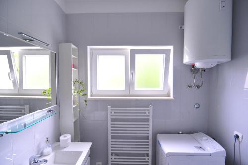 a bathroom with a sink and a toilet and two windows at A - luxury apt in center just 5min from beach in Korčula