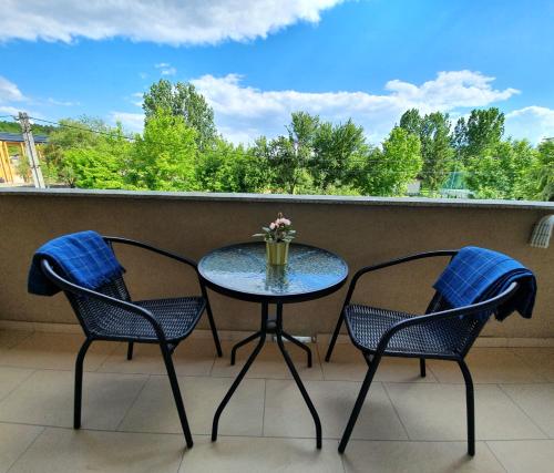 a table and two chairs on a balcony with a window at Harmónia Panzió in Bogács