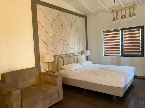 a bedroom with a large bed and a chair at Gradina Forest Villas in Sozopol
