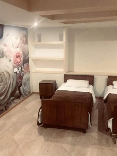 a bedroom with two beds and a painting on the wall at Guesthouse Raisa in Kvareli