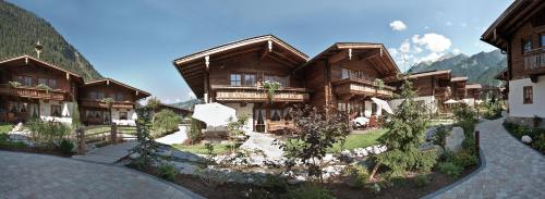 un grupo de edificios de madera con montañas en el fondo en Brugger ChaletDorf, en Mayrhofen