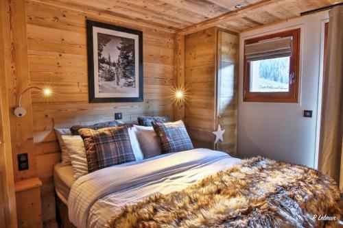 ein Schlafzimmer mit einem Bett in einer Holzhütte in der Unterkunft Astraea in Peisey-Nancroix