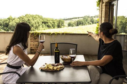 two women sitting at a table with a glass of wine at Poggio alle Vigne in Torgiano