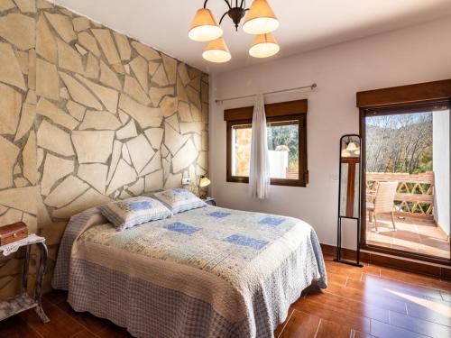 een slaapkamer met een bed en een stenen muur bij Casa del rio in Saleres