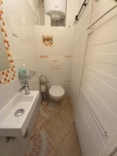a white bathroom with a toilet and a sink at Bunari Studio Apartment in Rovinj