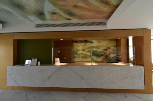 a lobby with a reception desk with a painting on the wall at Geraniotis Hotel and Resort in Plataniás