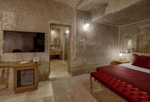 a bedroom with a bed and a tv in a room at Hera Cave Suites in Goreme