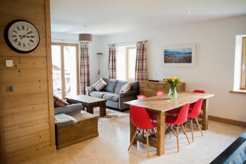 - un salon avec une table, des chaises et une horloge dans l'établissement 'Petite Ferme Les Bouts' Apartment, sleeps 6, Nr Morzine, à La Côte dʼArbroz