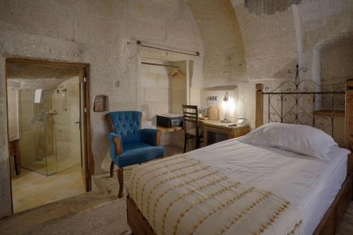 a bedroom with a bed and a chair and a shower at Hera Cave Suites in Goreme