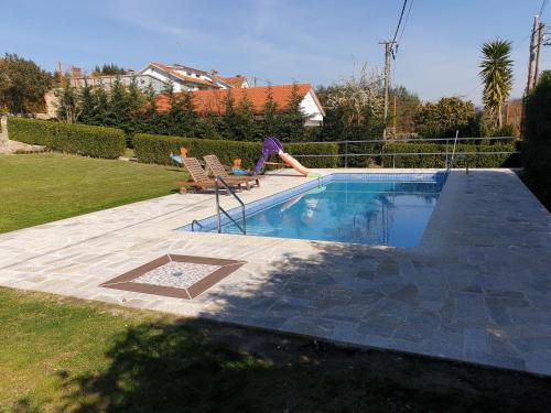 a swimming pool with two chairs and a person laying on avisor at CASA VEIGA in Pontevedra