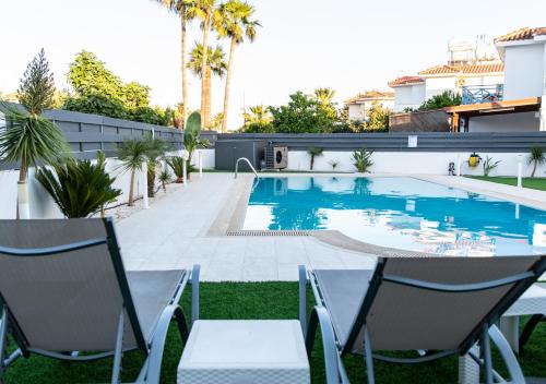 a swimming pool with two chairs and a table in a yard at Kypkeys Apartments in Voroklini