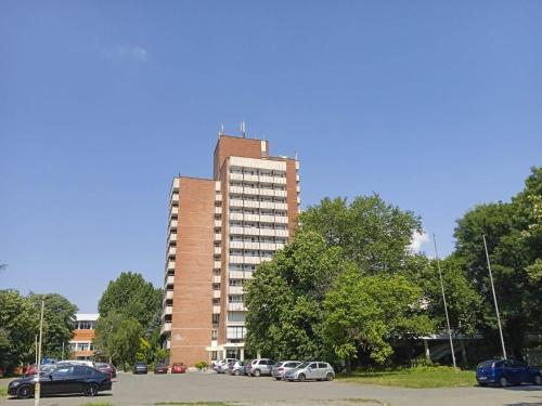 a tall building with cars parked in a parking lot at Hotel Park in Burgas City