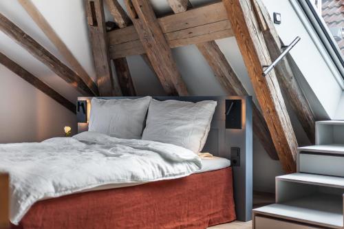 an attic bedroom with a bed and a large window at Hotel Die Reederin in Lübeck