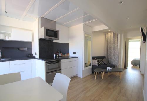een keuken en een woonkamer met witte kasten en een tafel bij La terrasse de Carras in Nice