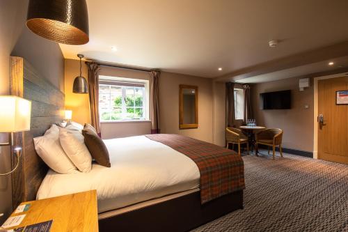ein Hotelzimmer mit einem großen Bett und einem Tisch in der Unterkunft The Partridge, Stretton in Stretton