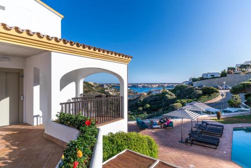 a house with a balcony with a swimming pool at Calallonga Hotel Menorca in Mahón