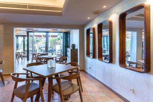 a dining room with tables and chairs and windows at Calallonga Hotel Menorca in Mahón