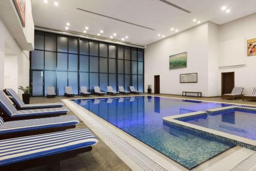 a large swimming pool with chairs in a building at Ramada Hotel & Suites by Wyndham Ajman in Ajman 