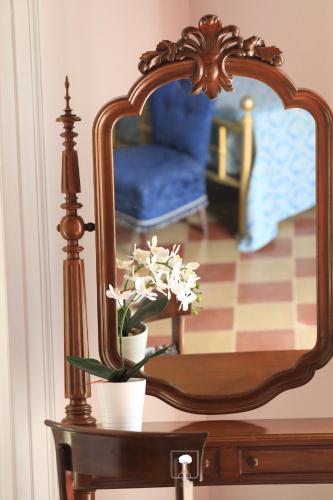 a table with a mirror and a vase with flowers at Le Due Sicilie in Tropea