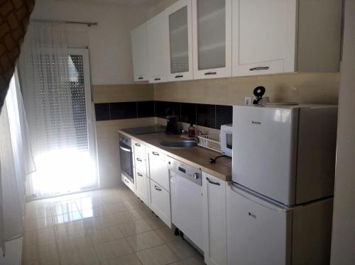 una cucina con mobili bianchi, un lavello e un frigorifero di Secret Garden a Neum