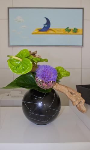 a purple flower in a black vase on a counter at Kyriad Prestige Perpignan Centre Gare in Perpignan