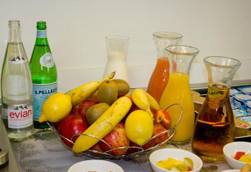 a bowl of fruit on a counter with bottles of juice at Kyriad Prestige Perpignan Centre Gare in Perpignan