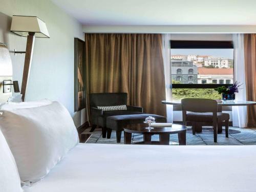 a hotel room with a bed and a living room at Sofitel Lisbon Liberdade in Lisbon
