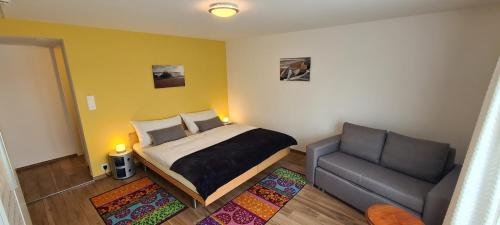 ein kleines Schlafzimmer mit einem Bett und einem Sofa in der Unterkunft Hôtel Restaurant Cave Bel-Air in Praz