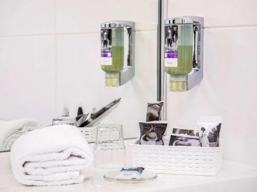 a bathroom counter with a towel and two lights at Mercure Hotel Hamm in Hamm