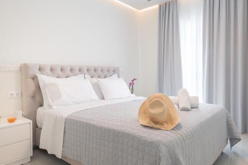 a white bedroom with a bed with a hat on it at Narya Luxury Apartment in Agios Rokkos