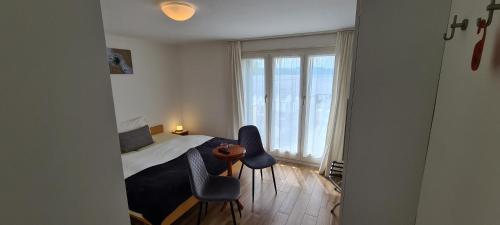 a bedroom with a bed and two chairs and a window at Hôtel Restaurant Cave Bel-Air in Praz