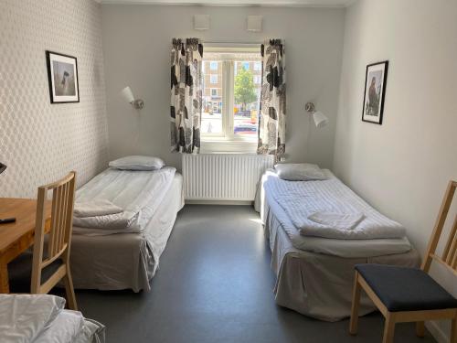 a room with two beds and a table and a window at Gefle vandrarhem in Gävle