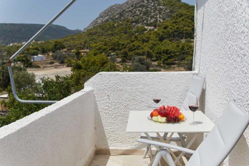 a table with a bowl of fruit and a glass of wine at Golden Star Praxitelous in Agia Marina Aegina
