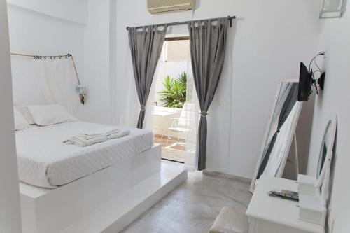 a white bedroom with a bed and a window at Golden Star Praxitelous in Agia Marina Aegina