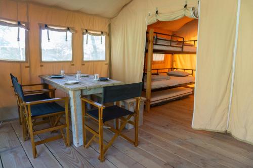 Tiendas safari Chill-Outdoor في Perarrua: غرفة مع طاولة وكراسي وسرير بطابقين