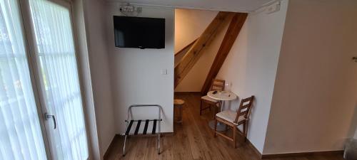 a room with a staircase and a tv on a wall at Hôtel Restaurant Cave Bel-Air in Praz