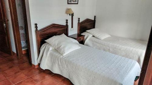 two beds in a room with white sheets at Hostal El Cascapeñas de la Alpujarra in Capileira