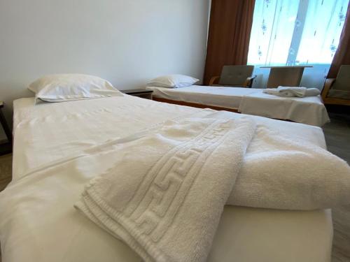 two beds in a hotel room with towels on them at Hotel Gorj in Târgu Jiu