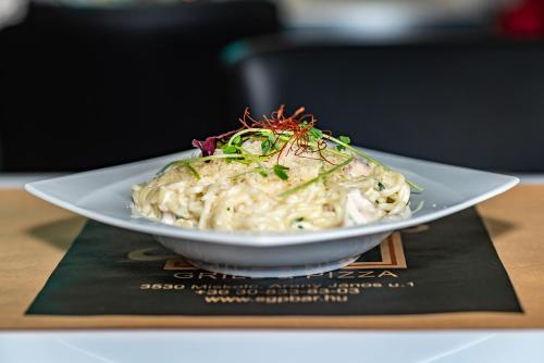 a bowl of noodles on a plate on a table at Arany Apartman Miskolc in Miskolc