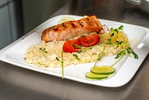 a plate of food with a piece of fish and rice at Arany Apartman Miskolc in Miskolc