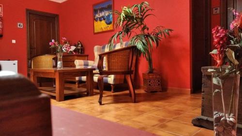 a living room with red walls and a table with a plant at Hostal El Cascapeñas de la Alpujarra in Capileira