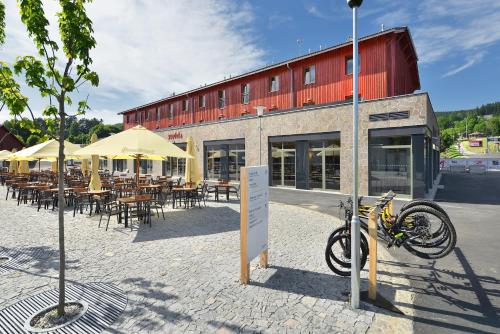 a bike parked in front of a building with tables and chairs at Hotel Element in Lipno nad Vltavou