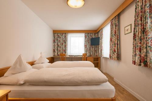 a bedroom with two beds and a television in it at Pension Angelo in Corvara in Badia