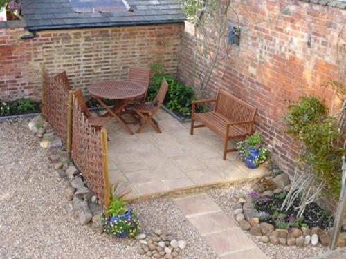 a patio with a table and chairs and a brick wall at Shepherds Row Bed and Breakfast in West Haddon