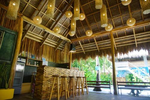 a restaurant with chairs and a bar with chandeliers at Hiraya Surf Hostel in General Luna