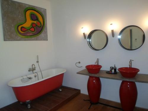 a bathroom with a red bath tub and two mirrors at Pavillon de Beauregard in Aix-en-Provence