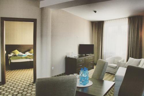 a hotel room with a living room with a bedroom at Hotel Nowy Zdrój - Centrum Zdrowia i Wypoczynku in Polanica-Zdrój