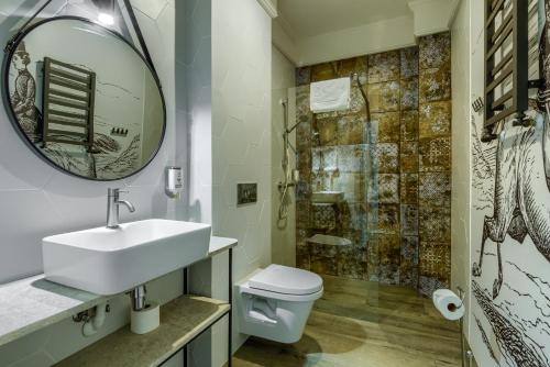 a bathroom with a sink and a toilet and a mirror at Kadyny Folwark Hotel & SPA in Kadyny