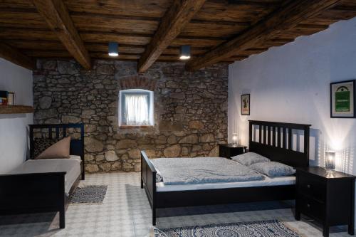a bedroom with two beds and a stone wall at Myrtus Borbár és Vendégház in Tarcal